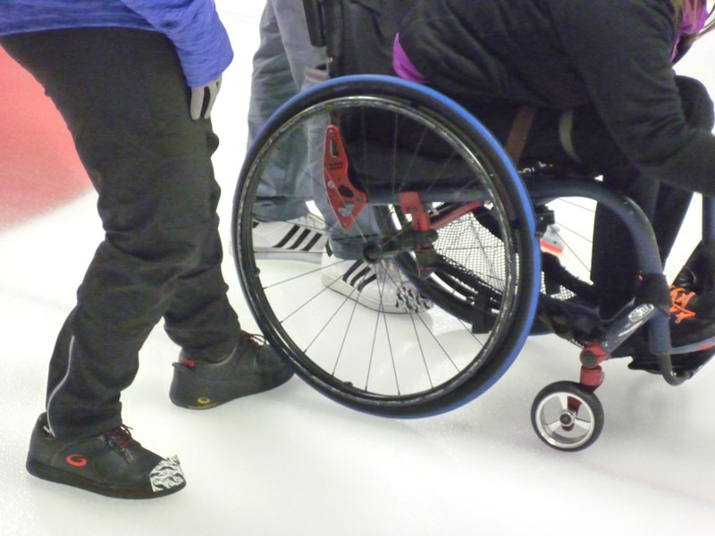 Opponent braces Pam's wheelchair as she delivers stones in play